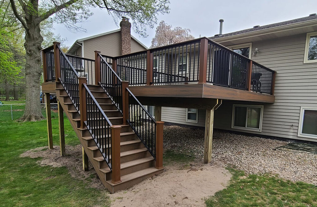 Two-story backyard deck with stairs and black metal railing, an Engelhard Construction project